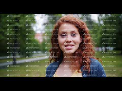 Portrait of girl student smiling looking at camera in green park on summer day