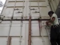 Manually lifting a shipping container with a car jack.
