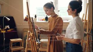 Professional teacher of art school is working with diligent girl student painting picture and