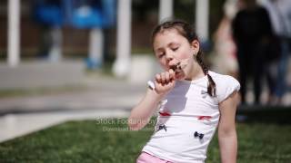 Cute Girl Eating Brown Ice Cream In The Park In The Summer Sunshine Day.