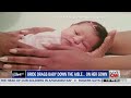Bride fastens baby to end of wedding dress