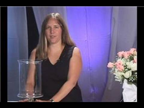 A container for a wedding centerpiece holds candles and flowers