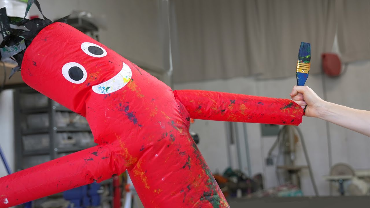Taping a paint brush to an inflatable tube guy