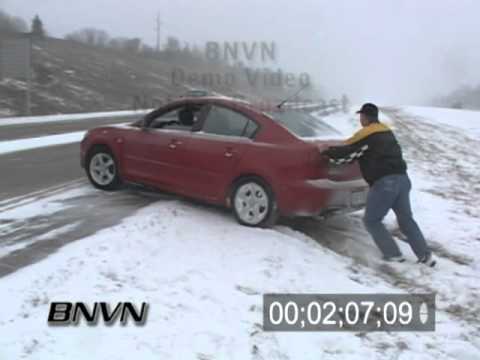 Freezing rain coats roads in the Charleston metro area during rush hour with an invisible layer of 'black ice'. A car spins out on the interstate dangerously close to the camera. An SUV loses control and leaves the road. The photographer moves closer to find that the SUV has rolled over into the ditch.