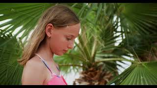 Cute Teen Girl Is Looking At Her Smartphone Standing Under The Palm Trees.
