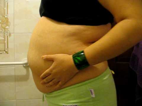 Girl plays with bloated belly after