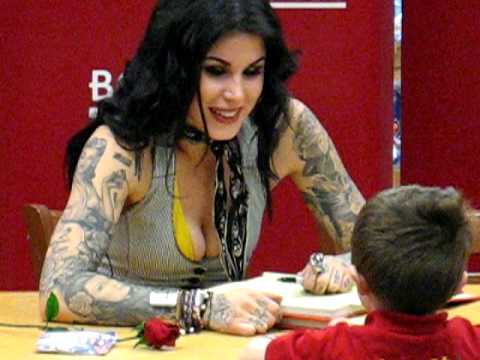 A little boy shows Kat Von D the tattoo on his arm while she's signing some