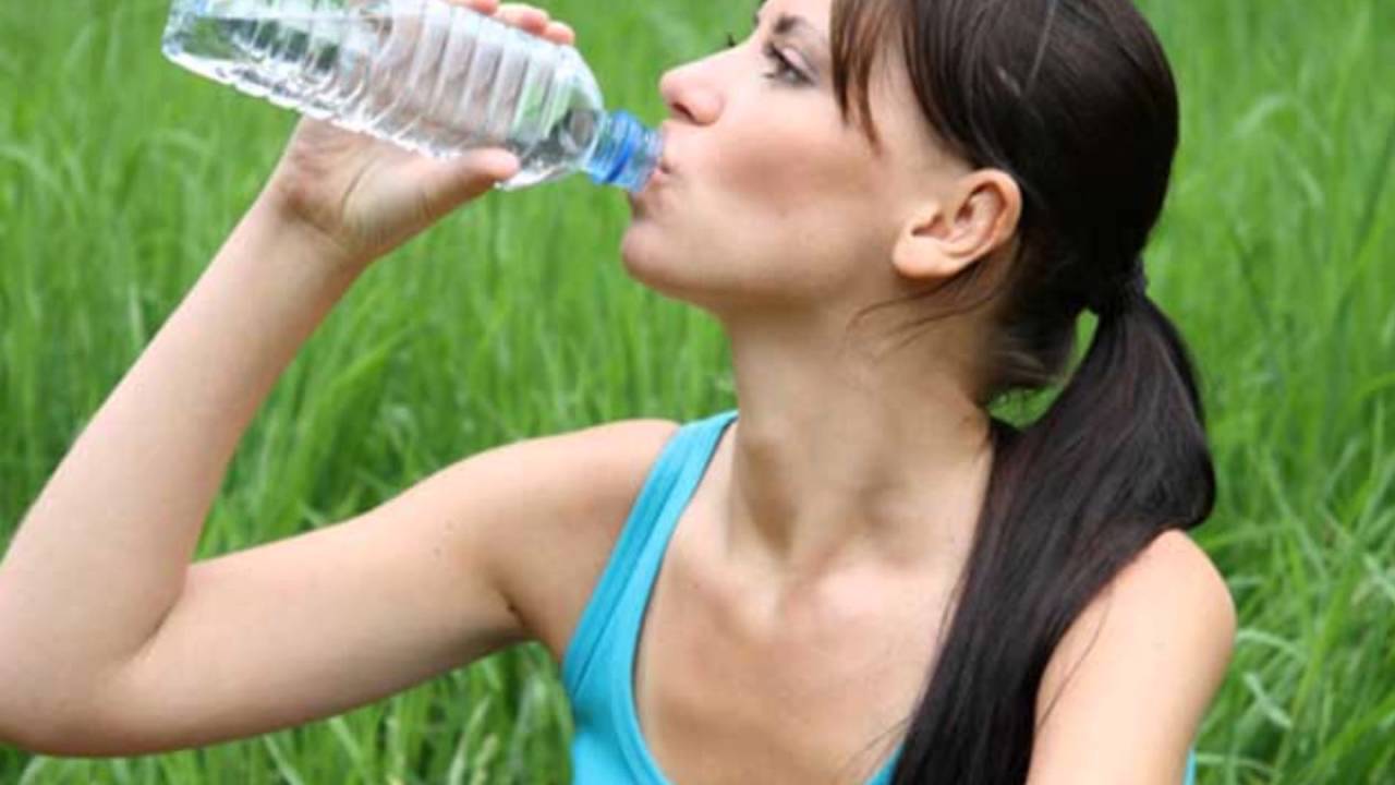 Пить. Женщина с бутылкой воды. Питье в жару. Жара человек пьет воду. Девушка пьет воду в жару.