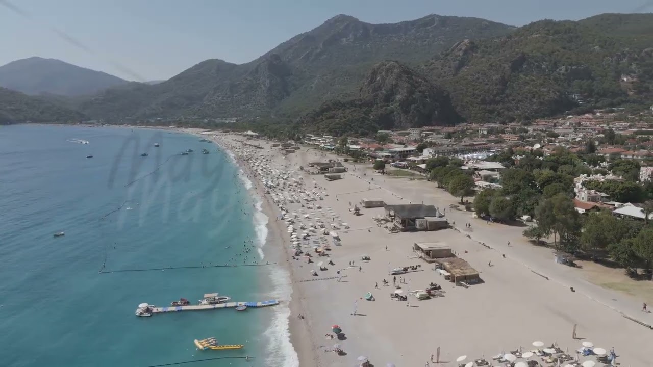D-Log M. Oludeniz, Turkey. Aerial view of Oludeniz Beach from water, people on sunbeds, wooden pi...