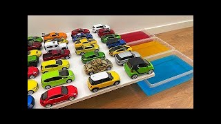 Various Diecast Model Cars Sliding Into The Red, Yellow And Blue Water