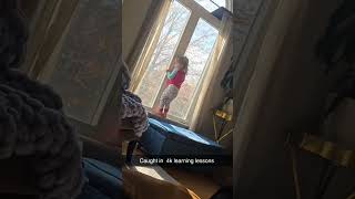 Little girl in pink pajamas walks on windowsill then falls down and brings window screen with her