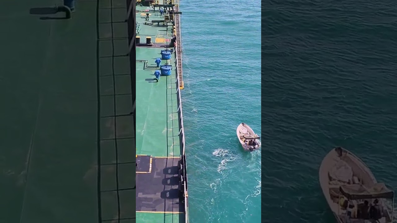 small boat alongside huge tanker ship at sea 