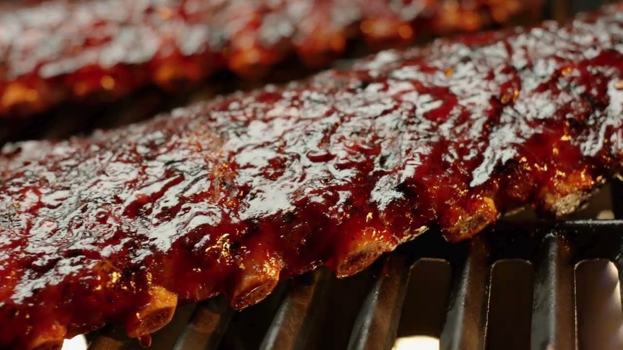 Close-up of ribs cooking on an open flame grill.