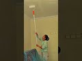 Painting a white ceiling with a long handled roller and applying even coats of paint in a home room