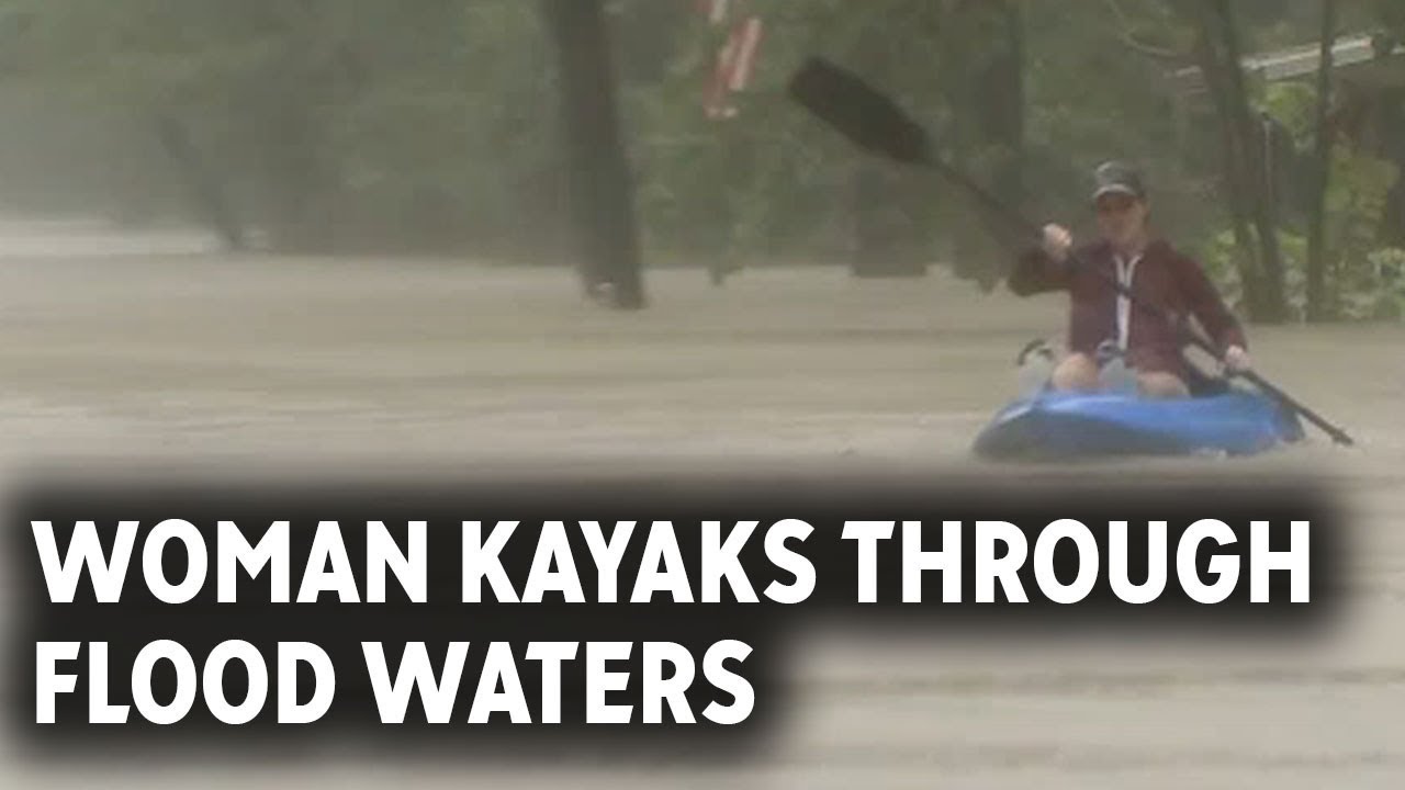 Residents traveling through flood waters in kayaks