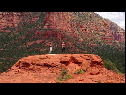 two women doing yoga on top of red rocks in sedona