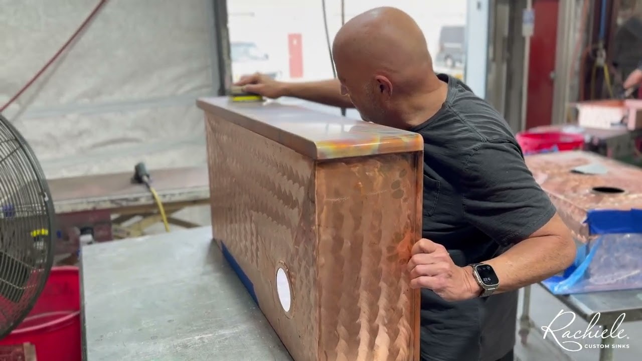 Hand refining clear coat on Fire and Ice patina custom apron front farm sink using 5000 grit sanding block for semi gloss finish