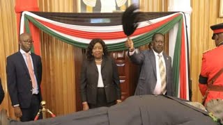 Raila Odinga waves his fly whisk as he views Moi's body