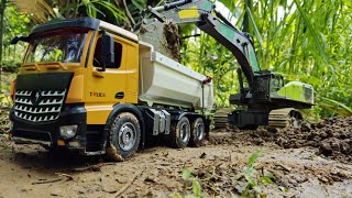 RC excavator scoops soil onto the truck. RC truck carrying soil climbs dangerous slopes