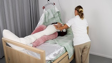 Immedia SatinSheet - One carer turning distressed user on side with cushion and hoist