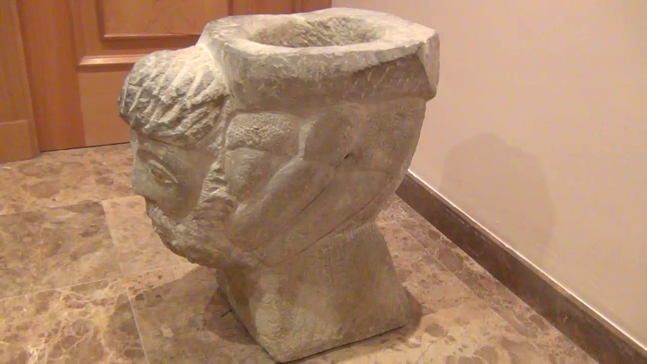 Bebedero de piedra con busto tallado