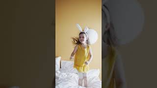 A Young Girl Jumping Up And Down On A Bed