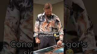 Conor McGregor signing the UFC 329 posters for his fight against Max Holloway