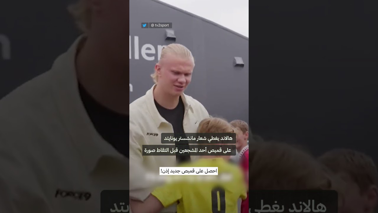 هالاند يغطي شعار مانشستر يونايتد على قميص أحد المشجعين قبل التقاط صورة تذكارية معه