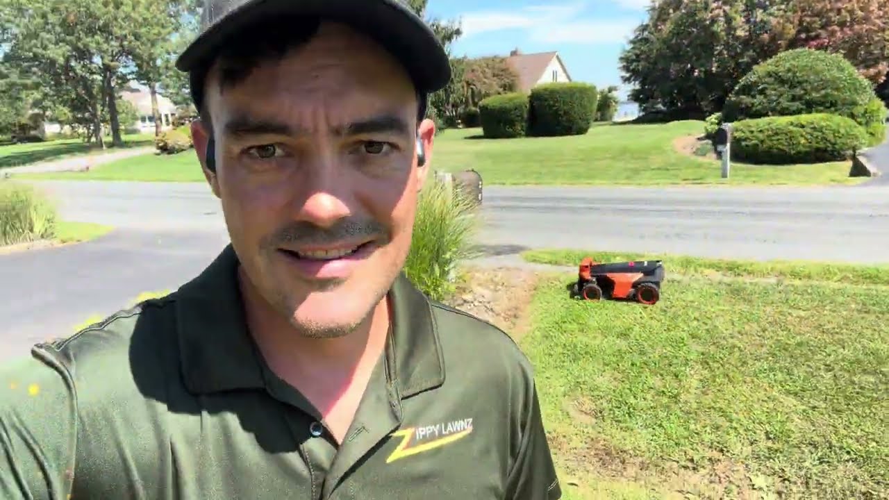 A Zippy Lawnz installer on a 3-acre Chester, Maryland property with a Segway Navimow Terranox robotic mower cutting the grass along the road behind him