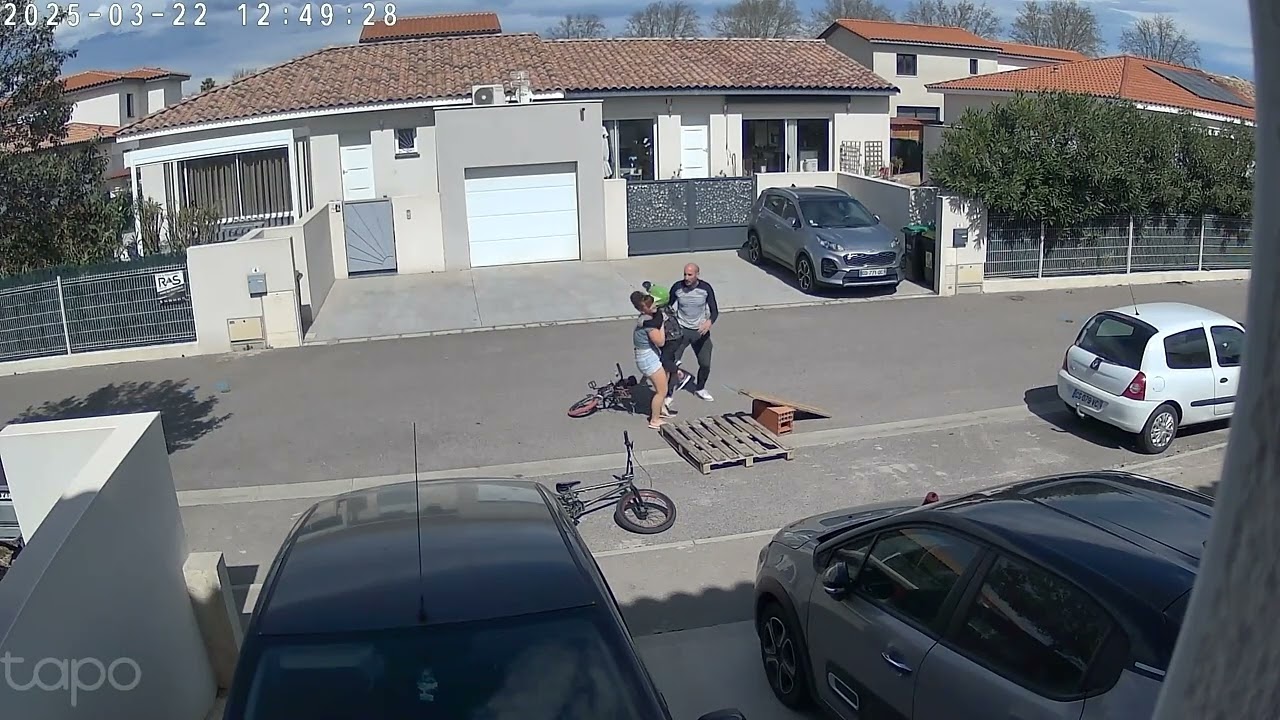 Boy in full face helmet on bike jumps homemade ramp in street and faceplants (Security camera)
