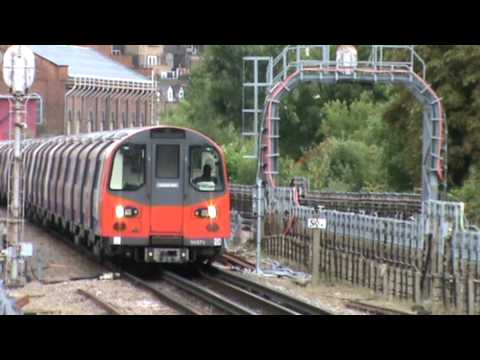 Chiltern Railways Class 165 Networker Turbo DMU heads south past West Hampstead Station towards London Marylebone, as a Jubilee line tube approaches the Station heading north, a southbound Metropolitan line train passes by, slowing to a stop in Finchley Road Station.