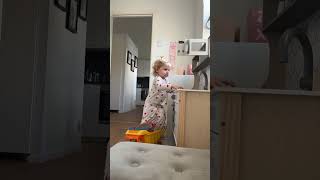 Little girl stands on top of toy truck and plays with microwave then kitchen falls on top of her