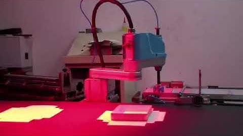 The scara robot uses red light vision for the assembly line