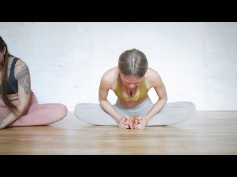 Two women performing yoga exercises on the floor..