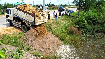 First dump truck unloading soil into the water landfill and bulldozer 31P working push stone fill