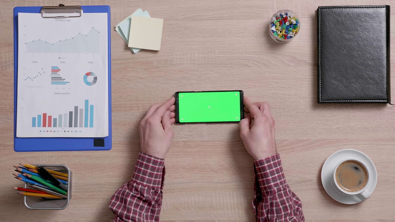 mans hands holding vertically a smart phone with green screen over