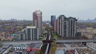 Commuter train passing through modern apartment buildings in Toronto, with city skyline on horizon