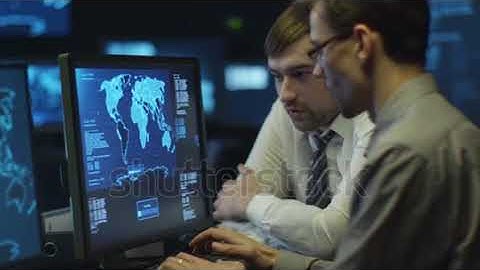stock footage two it programmers are working on computer in a dark office room filled with display s