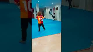 Little kid pushes punching bag then attempts to kick it but get hit by it and falls over