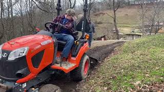 Kubota BX2380 cleaning a ditch and sloping a driveway.