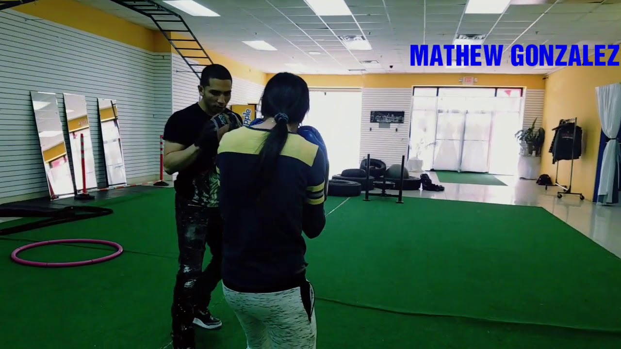 MATHEW GONZALEZ- WORKING WITH ONE HIS STUDENTS TO HIT THE BOXING MITTS