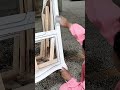 Sanding a white wooden chair frame meticulously by hand to smooth the surface before final painting