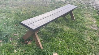 Sanding off old paint and applying a dark stain to a picnic bench