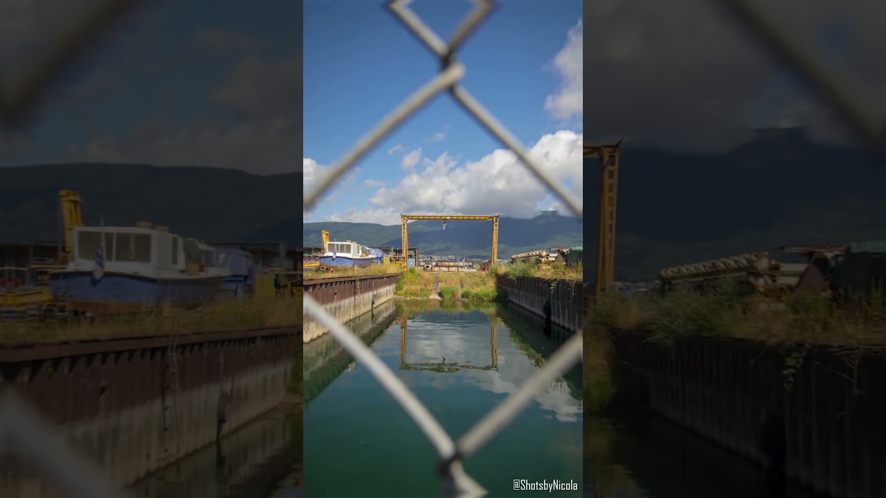 a photo of an old yellow crane through a fence by the water🏗📷 