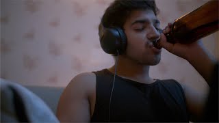 Indian young adult working on his laptop and drinking alcohol / beer