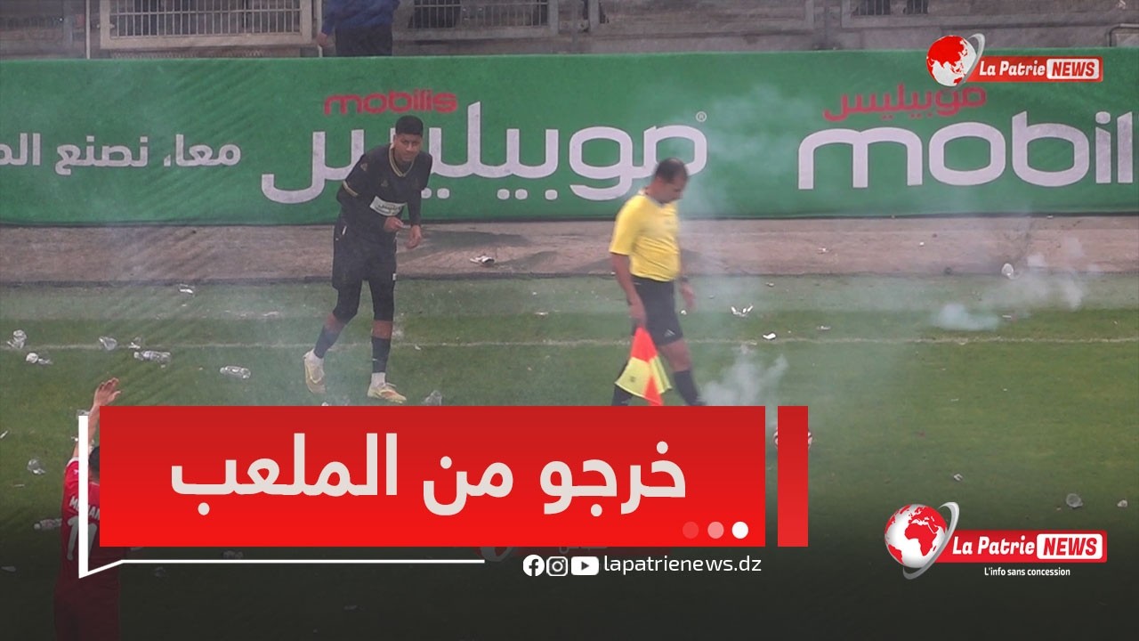 لاعب المولودية لم يستطع تنفيذ المخالفة بسبب المفرقعات و الحكم يتوجه لمراقب المباراة لتدوين التجاوزات