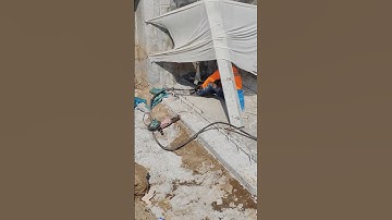 Workers breaking concrete sheet pile of boundary fence