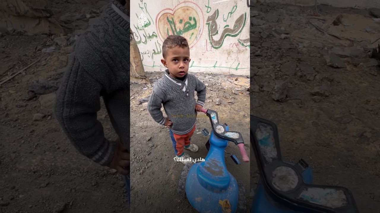 غزة.. طفل يلهو بدراجته أمام جثامين الشهداء