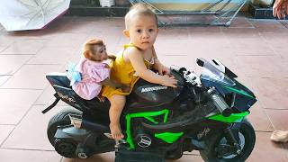 Monkey Kaka and Diem are sitting and riding a toy motorcycle.