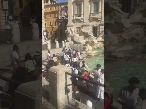 Tourist walks across Trevi Fountain in Rome to fill water bottle